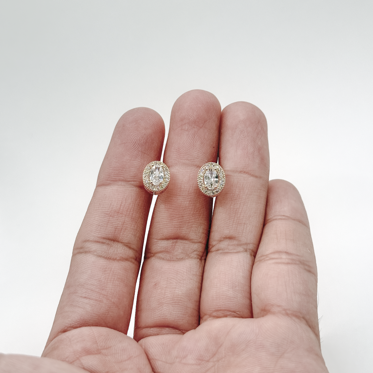 Broqueles dorados de chapa de oro con zirconia ovalada y contorno brillante