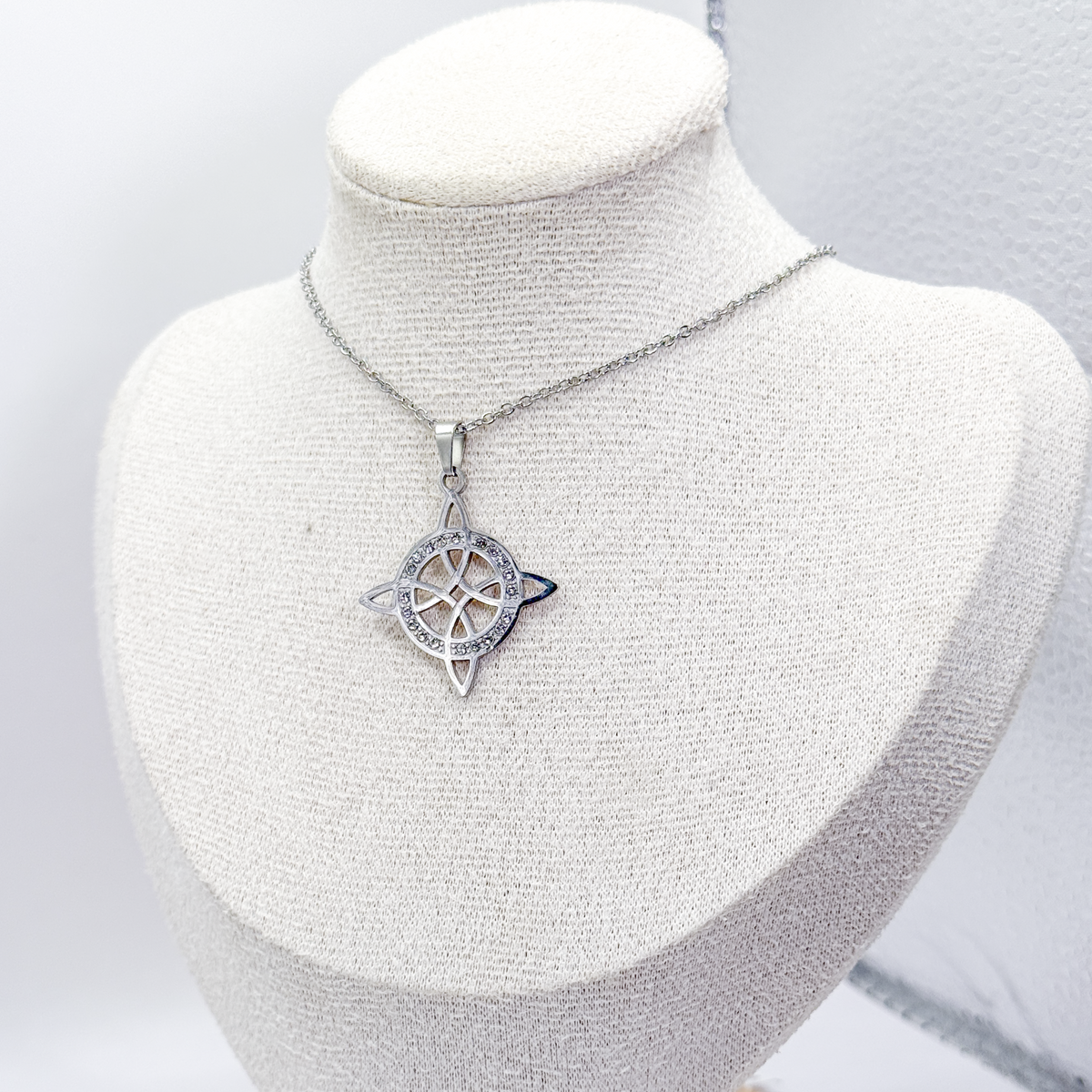 Collar plateado con dije de nudo de bruja decorado con zirconias