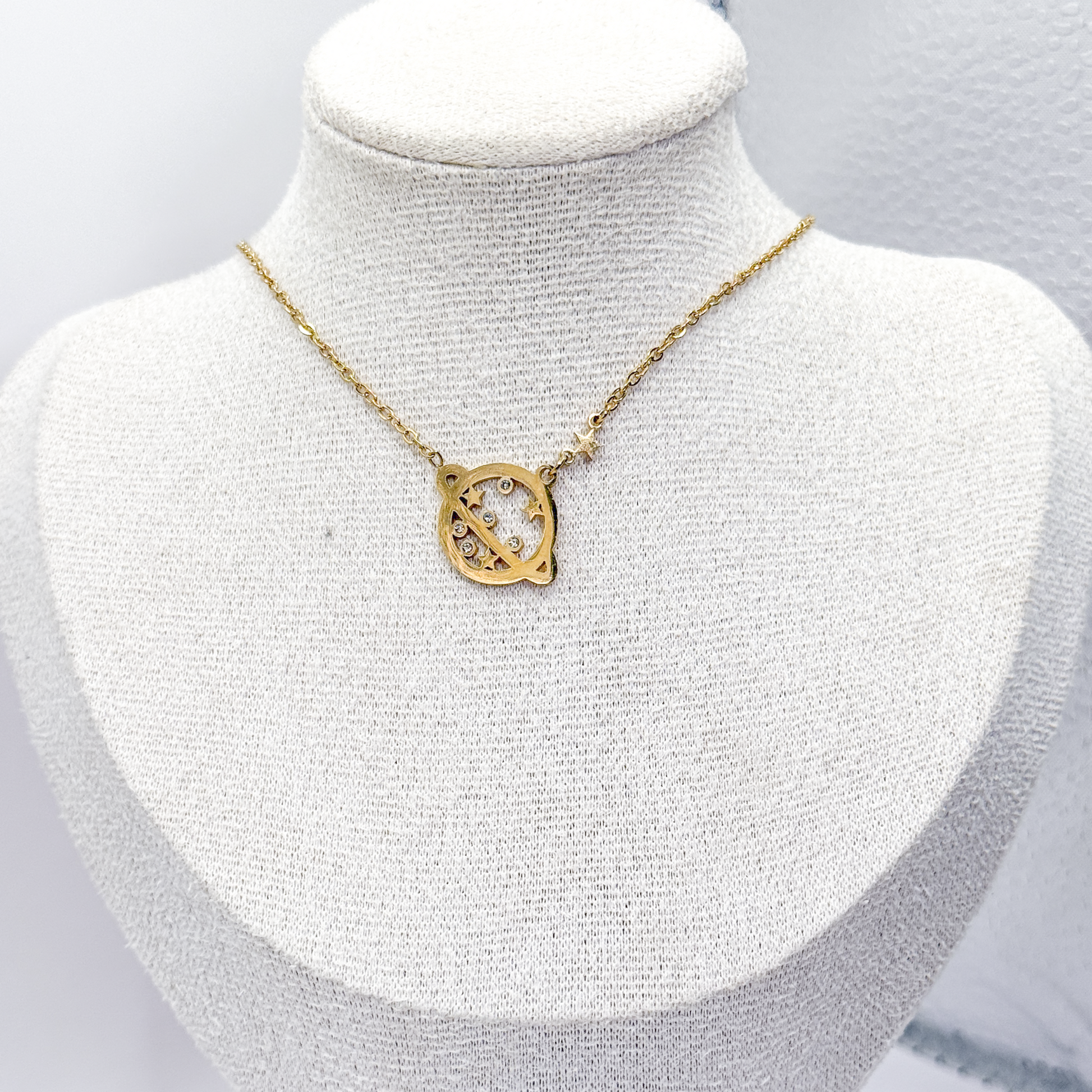 Collar dorado con dije de planeta, estrellas y zirconias