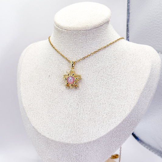Collar dorado inspirado en Enredados, con dije de sol, centro rosa giratorio y zirconias