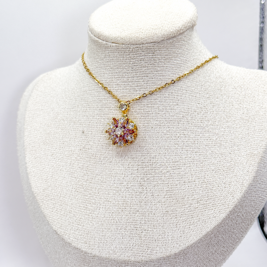 Collar dorado con dije circular giratorio de estrella rosa y zirconias