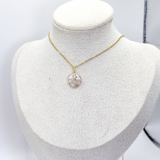 Collar dorado con dije circular de madre perla, estrella de mar y detalles de zirconia