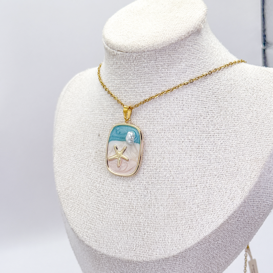 Collar dorado con dije rectangular de escena marina esmaltada, estrella de mar y detalle aperlado