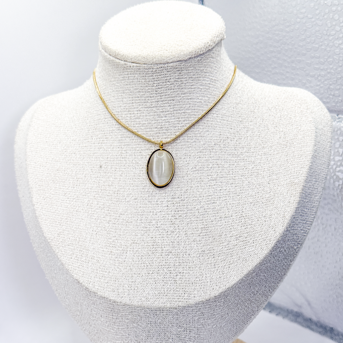 Collar dorado con dije ovalado de piedra ojo de gato blanca